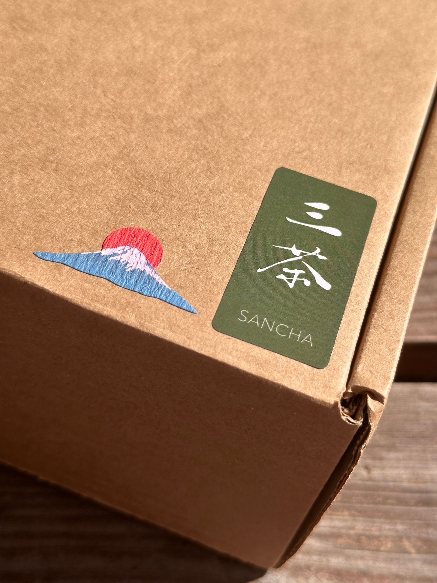 Kraft Sancha shipping box sealed with a Mount Fuji sticker and a matcha-green kanji label